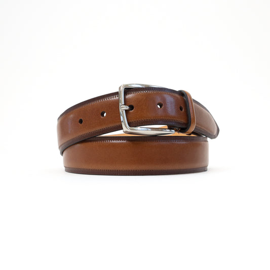A handmade Italian brown leather belt with a smooth finish and a silver-tone buckle, elegantly rolled for display.
