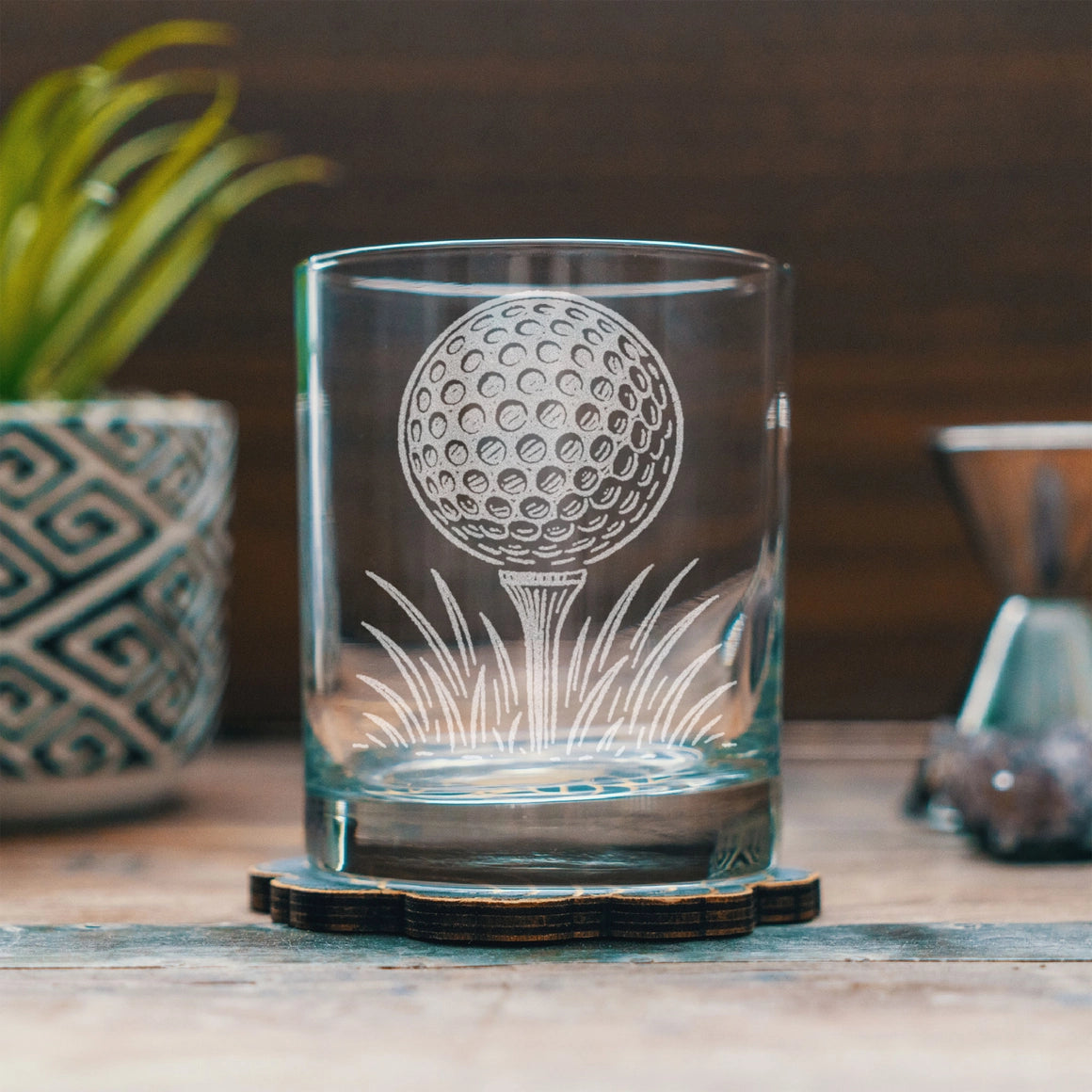 Clear glass tumbler with golf ball design on a wooden surface